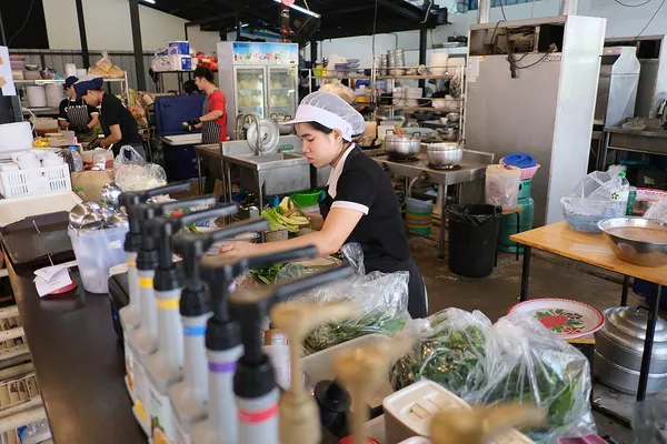 Kitchen worker in a hair net preparing fresh vegetables at a stainless-steel counter
