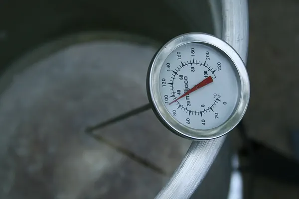 Dial food thermometer clipped to a pot to read the temperature