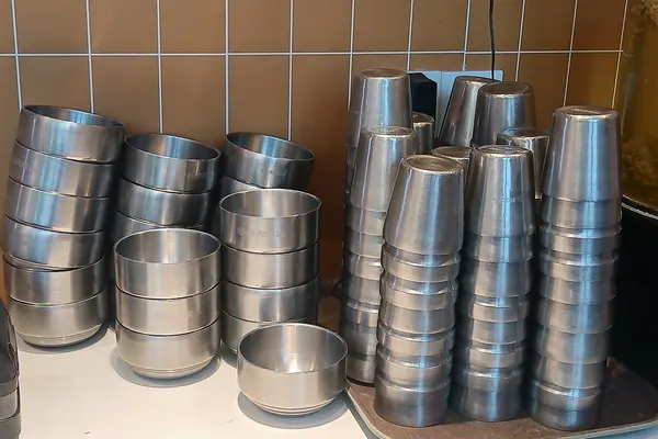 Clean stainless steel bowls stacked upside down on a kitchen shelf