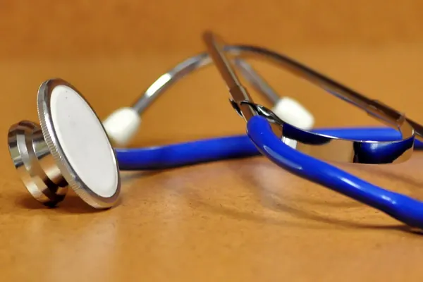 Blue stethoscope lying on a wooden table